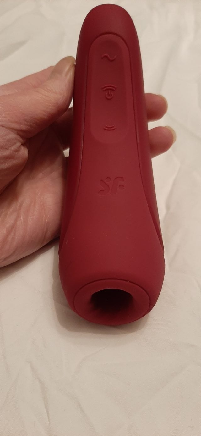 A person's hand holding a red sex toy - Satisfyer Curvy1+.