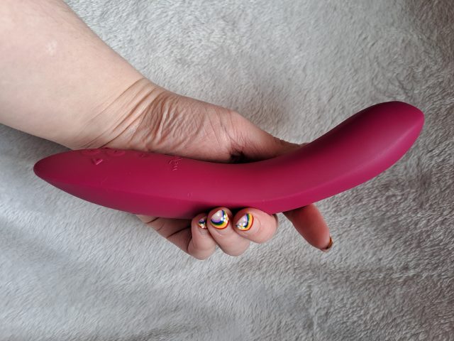 A woman's hand holding a pink vibrator, specifically the We-Vibe Rave 2.