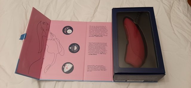 A pink and blue box with a Satisfyer Curvy1+ sex toy inside.