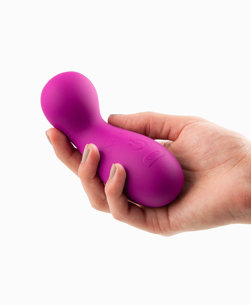 A woman's hand holding the Cliona launch, a pink vibrating toy by Kiiroo.