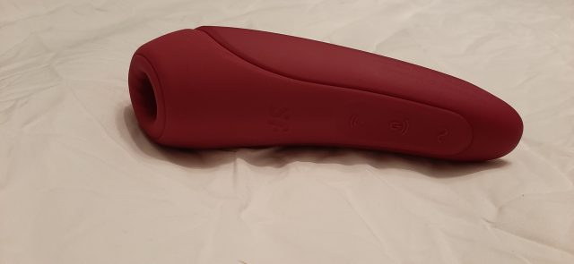 A Satisfyer Curvy toy discreetly displayed on a bed.