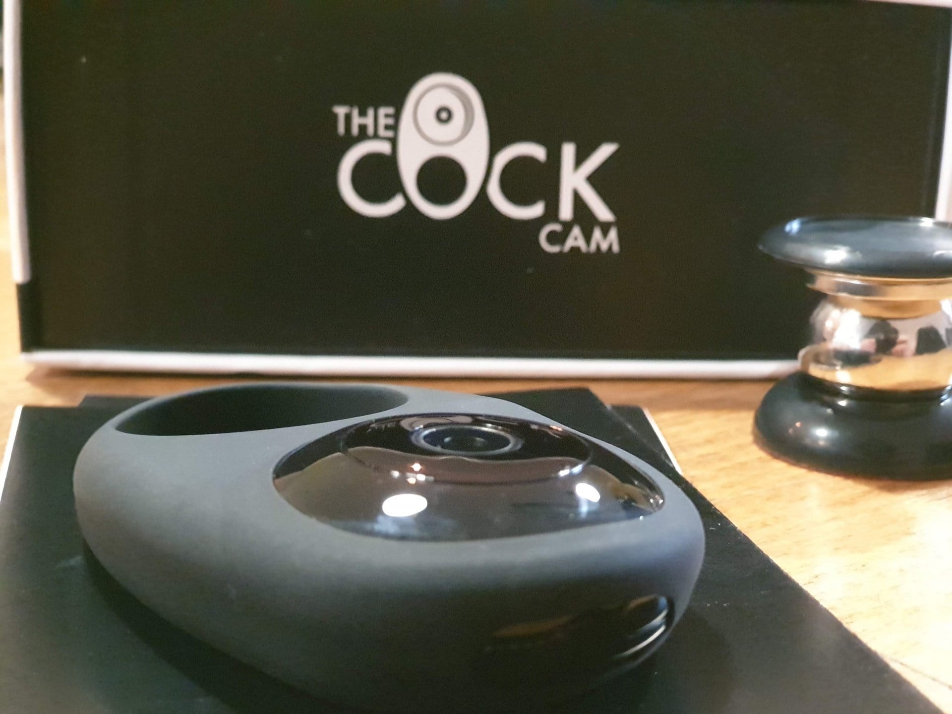The CockCam review showcases the device placed on a table alongside a box.