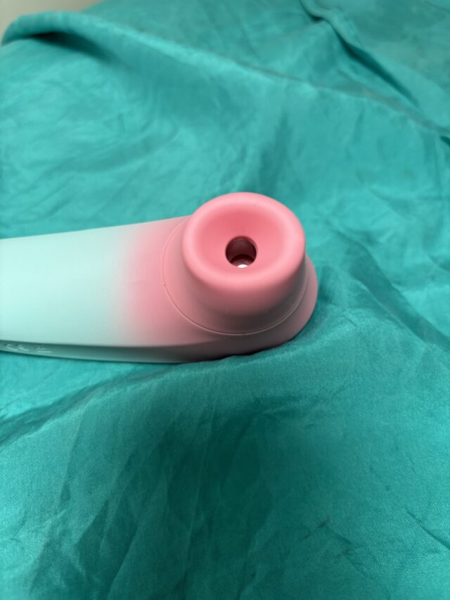 Silicone sex toy with a pink opening on a teal fabric background, showcasing a modern and ergonomic design. Ideal for adult pleasure products, intimacy enhancement, and sextech innovations.