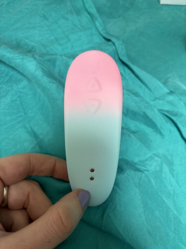 Wireless sex tech device with LED lighting on a teal fabric background, designed for intimate pleasure and sexual wellness.