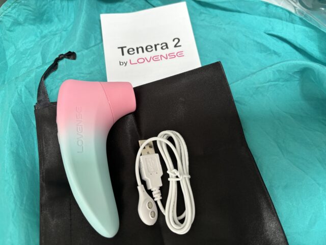 Pink and mint Lovense Tenera 2 vibrator on black fabric with USB charging cable; popular sex tech device for intimate pleasure.