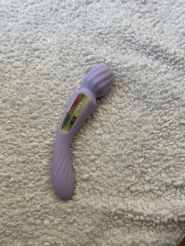 Silicone vibrator with gold accents on a plush, textured white surface, designed for intimate pleasure and personal wellness.