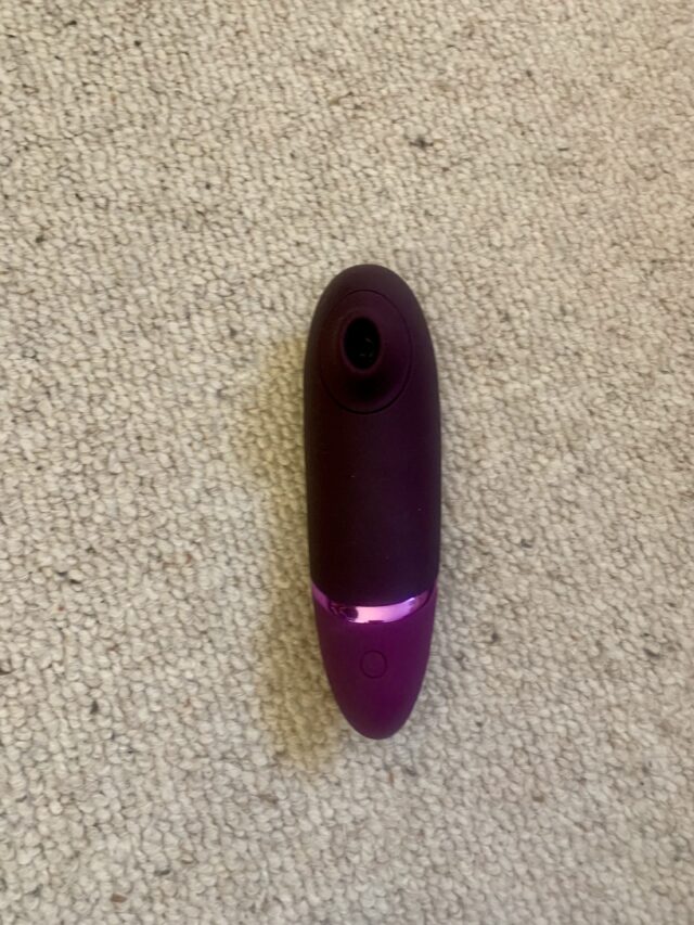 A womanizer device resting on a carpet for its next review.