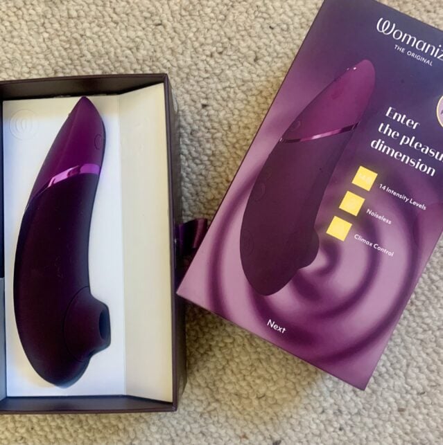 A purple vibrator in a box on the floor awaits its next review.