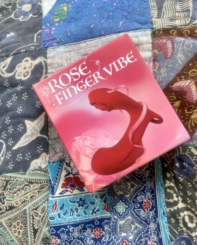 Rose finger vibrator sex toy on colorful quilt, body-safe personal massager designed for intimate pleasure and sensory stimulation, perfect for adult use and exploring sexual wellness and self-care.