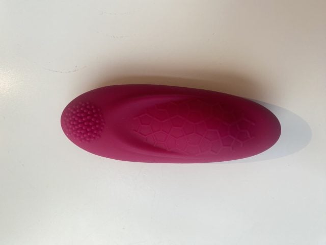 Small pink silicone vibrator with textured surface and honeycomb pattern for enhanced pleasure. Cordless, discreet design ideal for personal intimacy and sexual wellness routines.