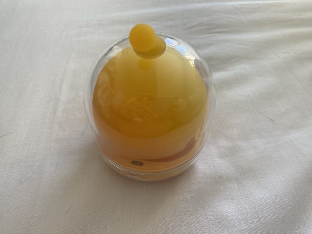 Yellow scented candle with a round wick inside a clear plastic container, stylishly designed for relaxation and ambiance enhancement.