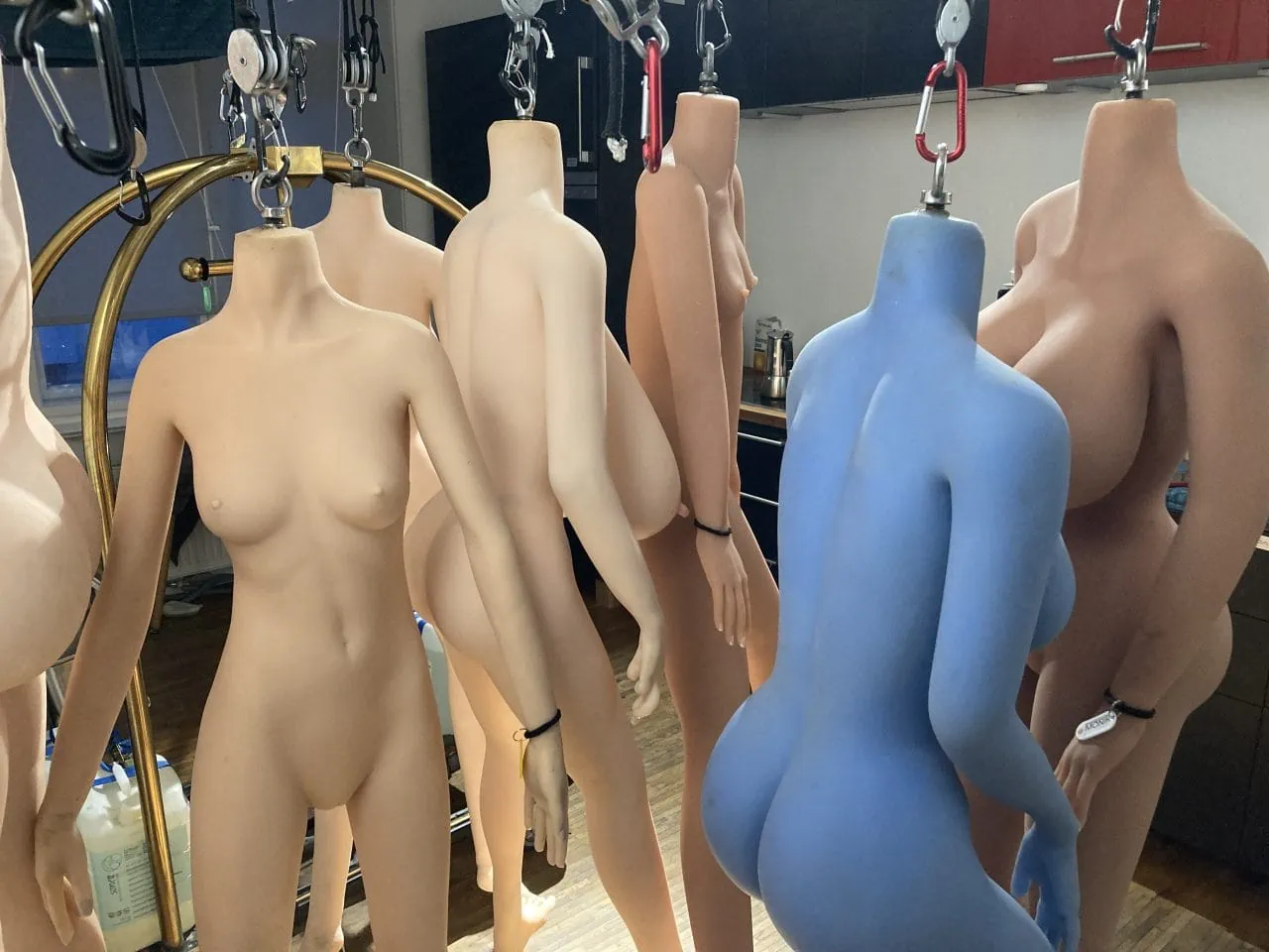 Mannequins hanging in a blue room with cyberbrothel vibes.