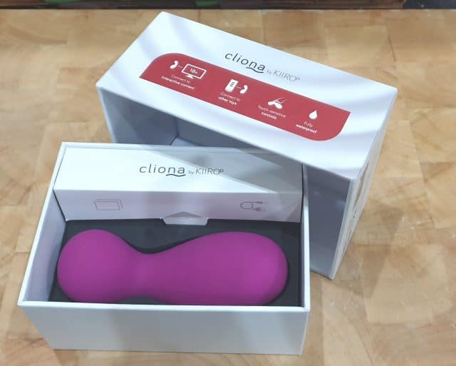 A Kiiroo Cliona review featuring a pink sex toy box on a table.