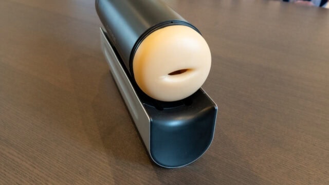 Fleshlight male sex toy with realistic oral opening resting on a charging dock for optimal pleasure simulation.