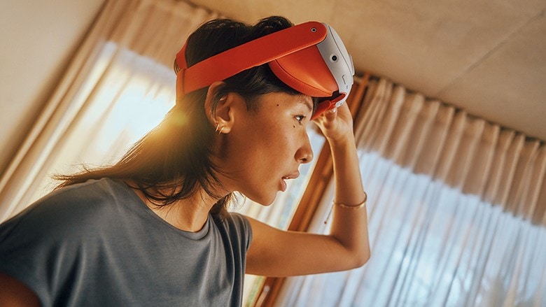 A woman wearing a Meta Quest 3 VR headset in front of a window.