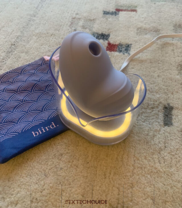 A Namii device with a blue light is sitting on a rug.