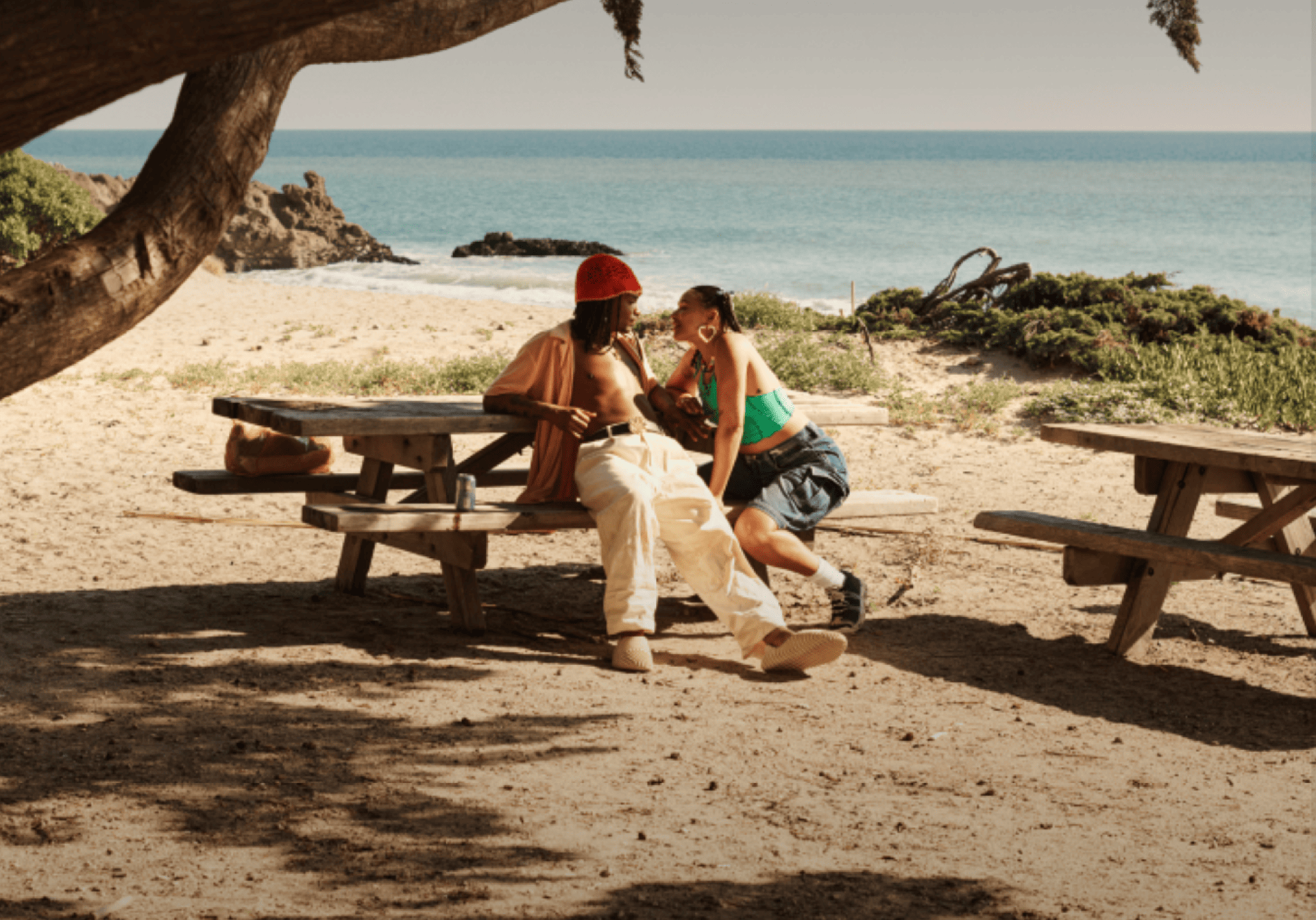 A couple on a picnic table at the beach enjoying a date.