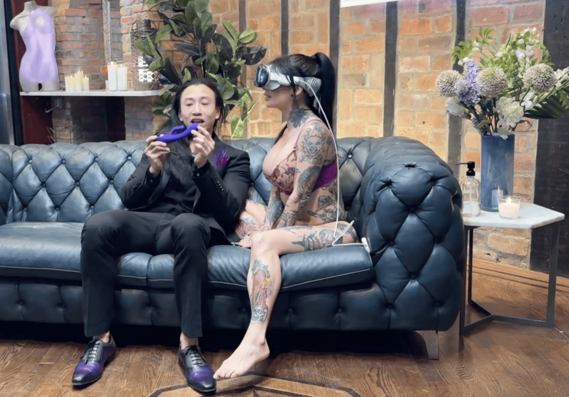 A man and woman sitting on a couch with tattoos.