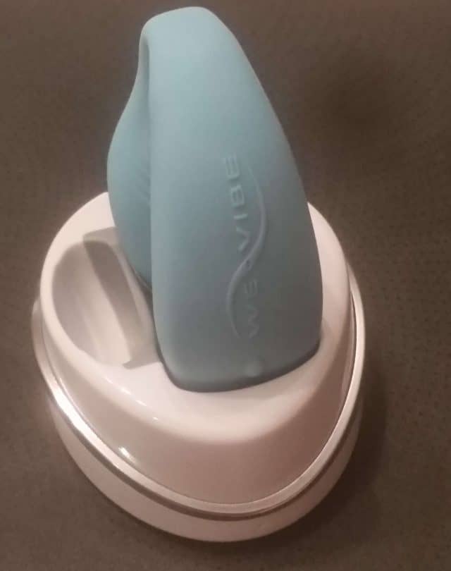 A review of the blue and white WeVibe Sync vibrator sitting on top of a table.