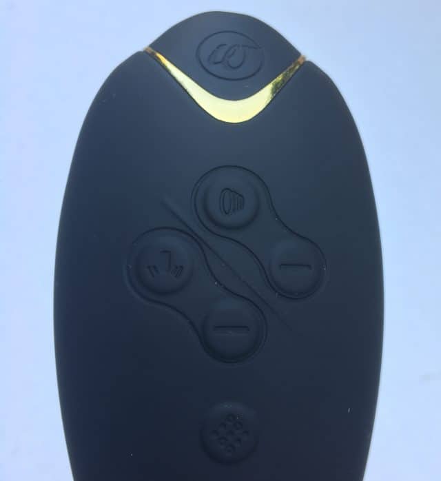 A Womanizer DUO remote control with golden accents.