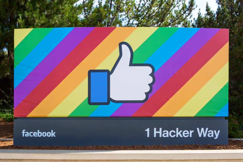 A rainbow-colored thumbs up sign in front of a Facebook building.