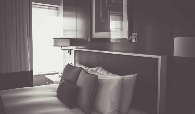 A monochrome image showcasing a cozy hotel bed.
