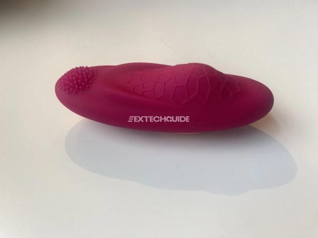 A pink ohmibod toy on a white surface.