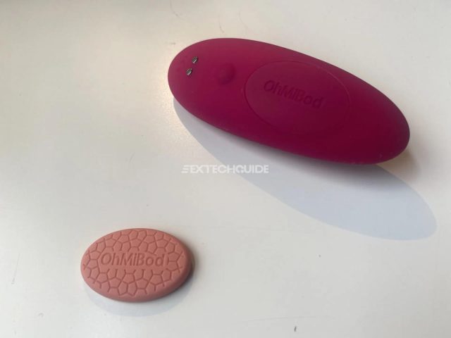 A ohmibod remote control next to a pink button.