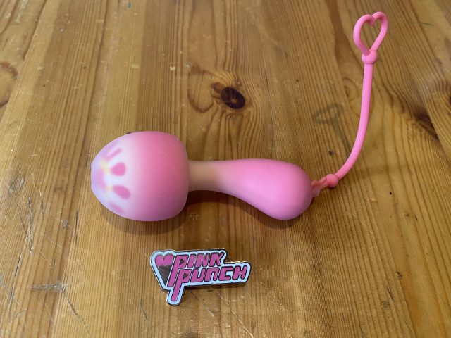 A pink mushroom toy on a wooden table.