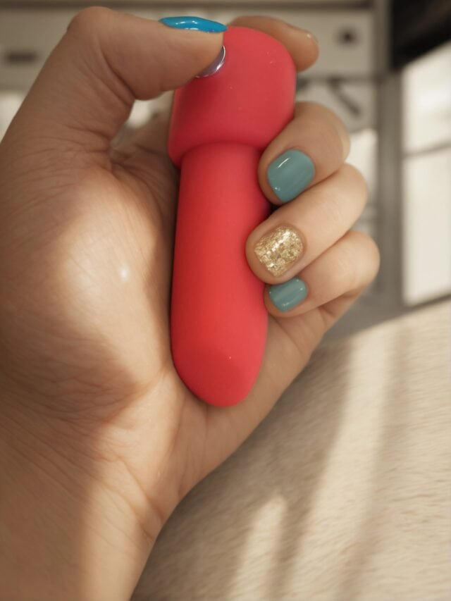 Pink sex toy held in hand with colorful manicured nails, showcasing intimate adult product for pleasure and wellness.