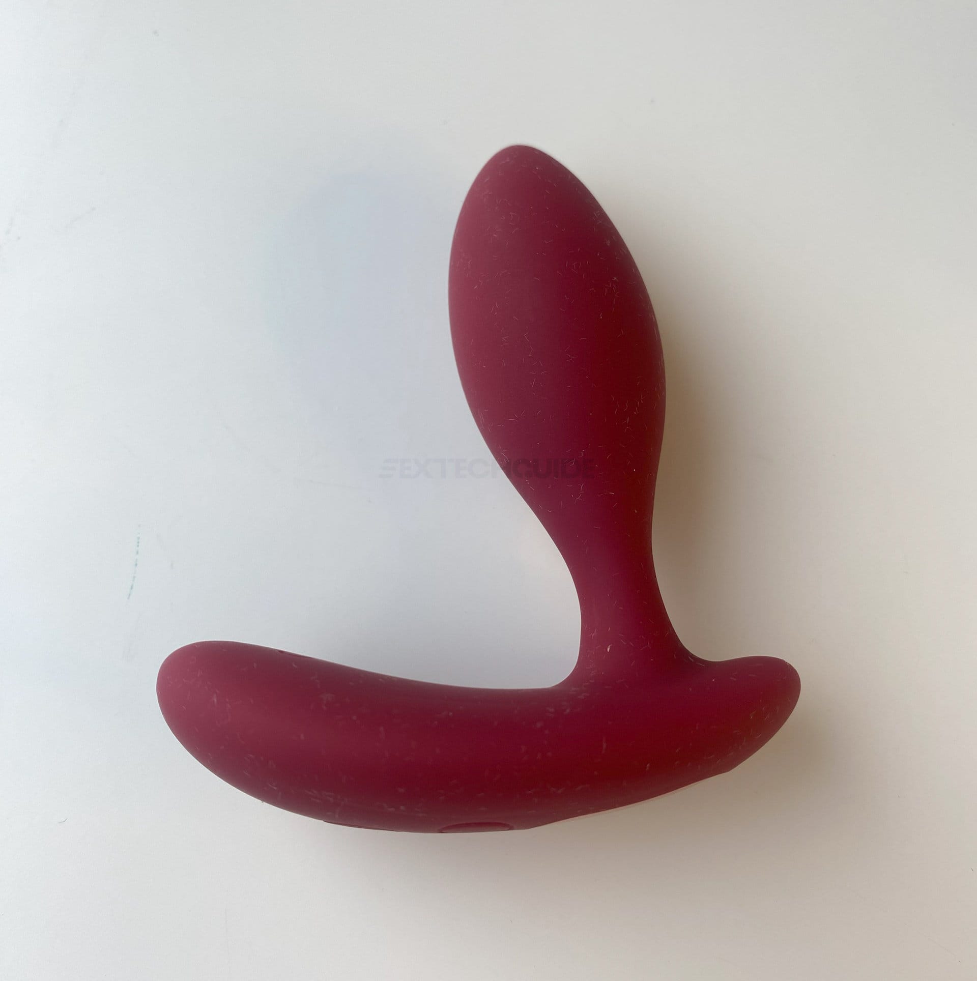 A red sex toy on a white surface, designed for enhancing pleasure.