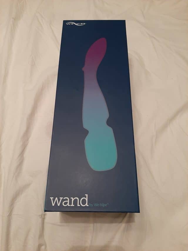 A We-Vibe Wand inside a box placed on a bed.